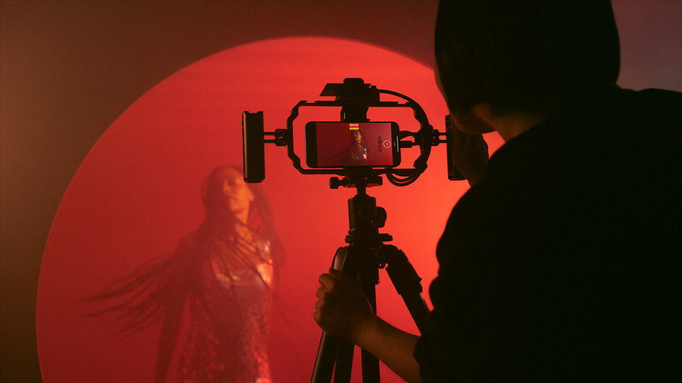 Fotografie osoby, která iPhonem na stativu natáčí barevné video ženy